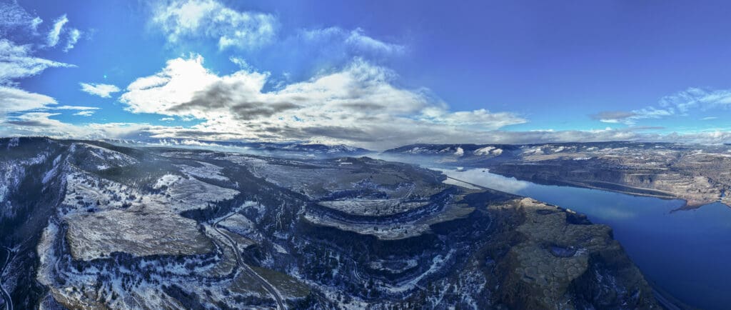 Winter aerial drone photograph of snow-covered Rowena Crest beneath dramatic clouds in the Columbia River Gorge near Mosier, Oregon, photographed by Tobi Rose Photography.