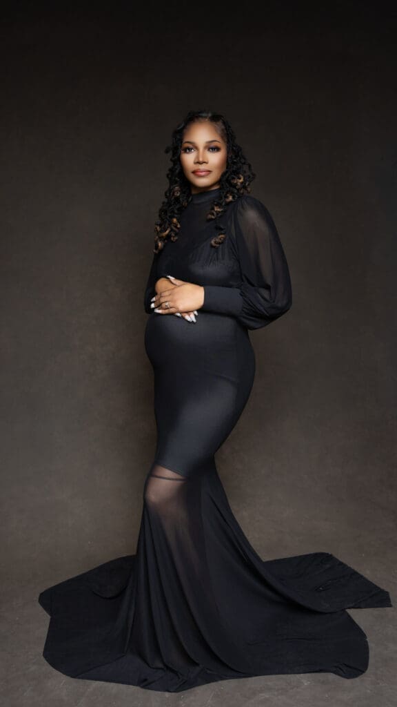 Full-length maternity portrait of a pregnant woman wearing a fitted black gown and cradling her baby bump, photographed by Tobi Rose Photography in Hood River, Oregon
