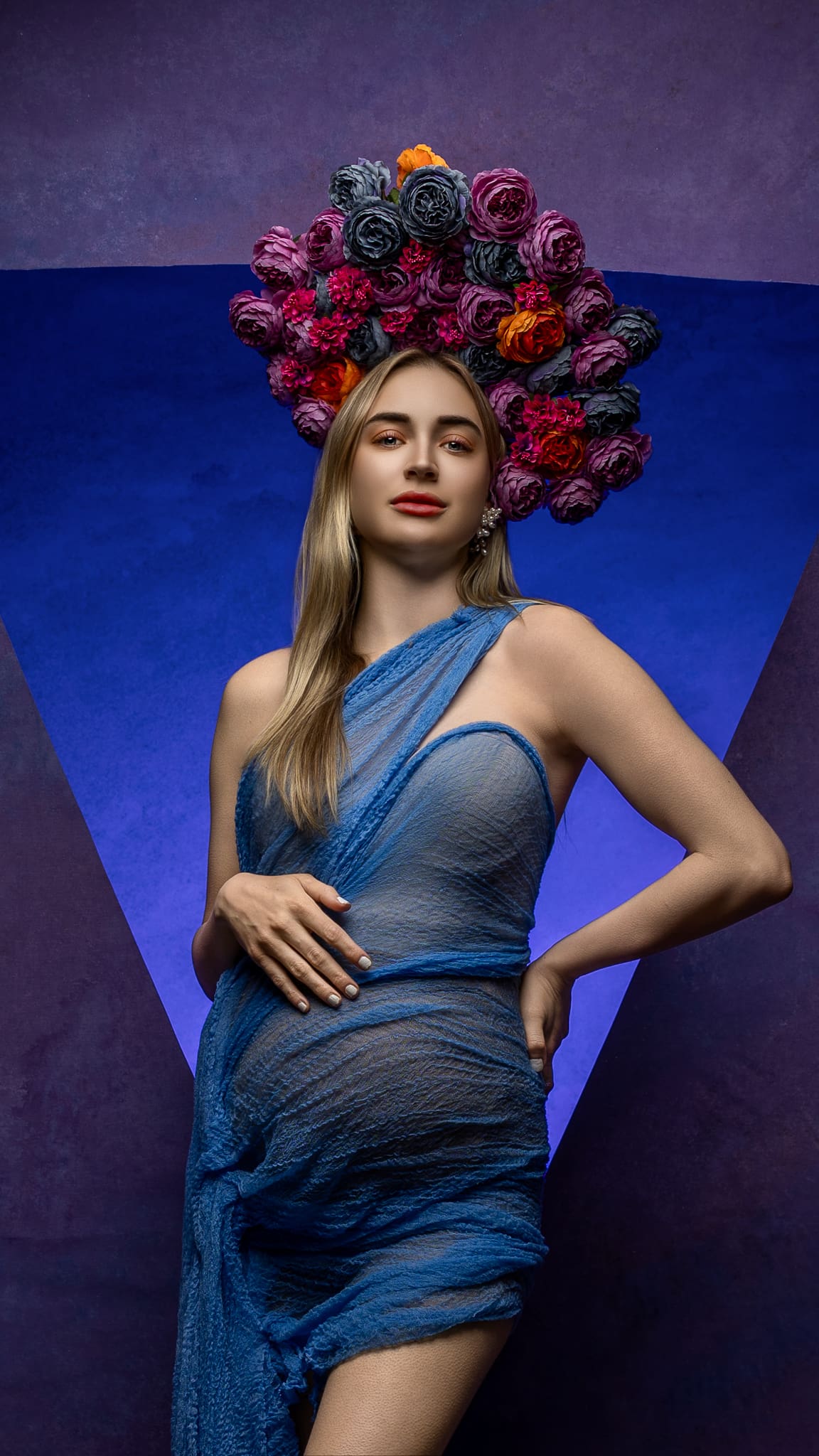 Pregnant woman posing in a fitted blue maternity dress with a colorful floral crown during a maternity portrait session by Tobi Rose Photography in Hood River, Oregon