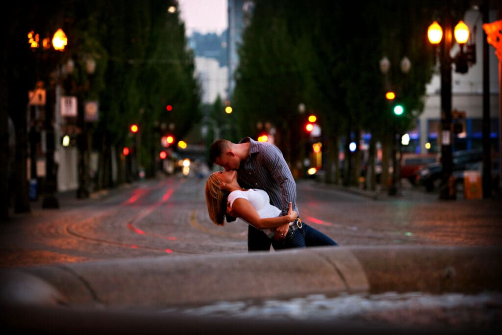 Engaged couple kissing in the middle of a downtown Portland street at night during an engagement session photographed by Tobi Rose Photography