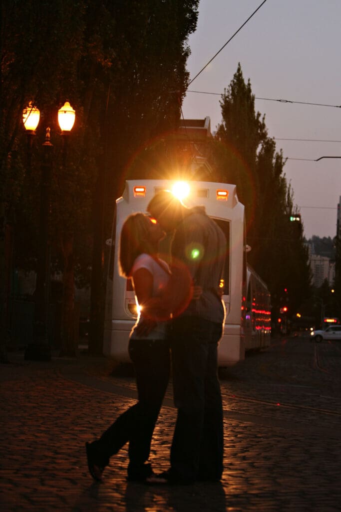 Engaged couple silhouetted beneath glowing streetlights at night during a downtown Portland engagement session photographed by Tobi Rose Photography