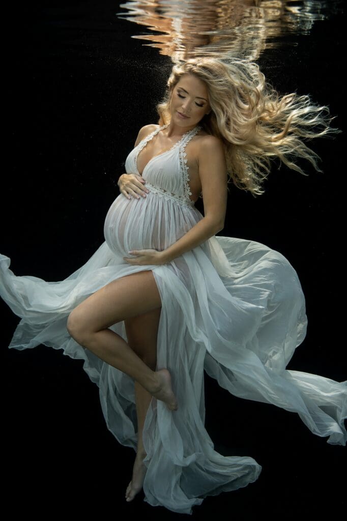 Underwater maternity portrait of a pregnant woman in a flowing white dress photographed in a pool in Hood River, Oregon, by Tobi Rose Photography