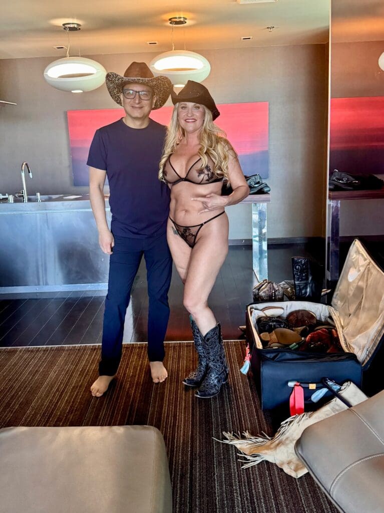 Tobi Rose Rabaliati with boudoir photographer Marco Ibáñez wearing cowboy hats during her Las Vegas penthouse boudoir session.