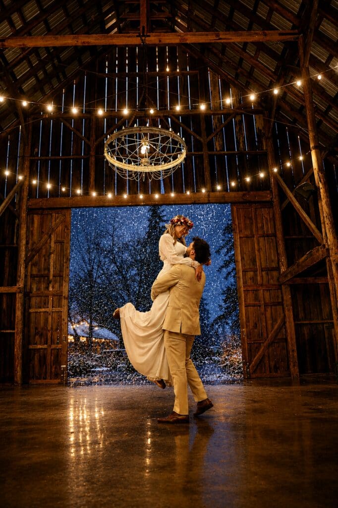 Groom lifting his bride inside the rustic Tin Roof Barn during a winter wedding in the Columbia River Gorge near White Salmon, Washington, photographed by Tobi Rose Photography