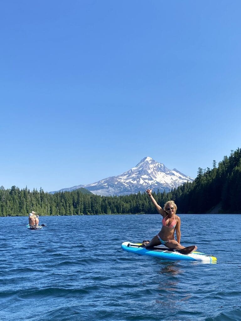Tobi Rose Rabaliati doing the splits on a paddleboard at Lost Lake with Mount Hood in the background in Oregon.