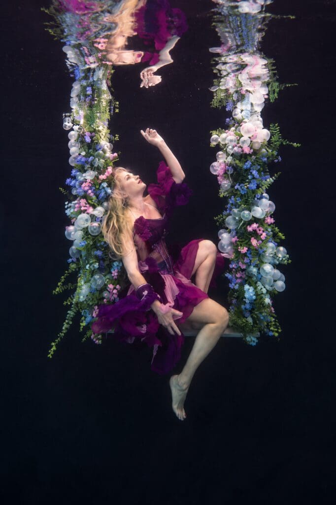 Tobi Rose Rabaliati modeling underwater among colorful hanging flowers in Kimber Greenwood’s pool in Gainesville, Florida, photographed by Kimber Greenwood of Water Bear Photography.