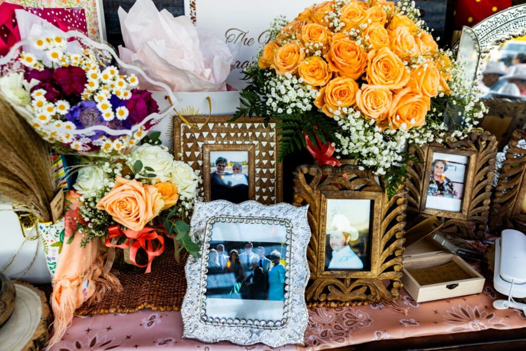 Memorial table with framed family photographs and flowers honoring deceased loved ones at Letty’s 50th birthday celebration in Hood River, Oregon.