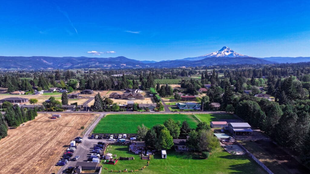 Aerial drone view of Letty’s 50th birthday party in Hood River, Oregon, featuring guests, live music, food vendors, photo booths and a mechanical bull with Mount Hood in the background, photographed by Tobi Rose Photography.