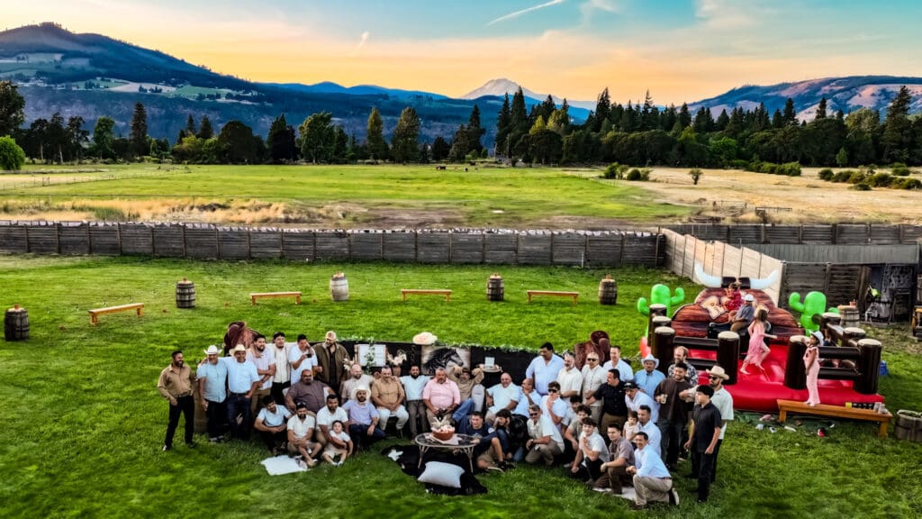Aerial drone photograph of the men gathered at Letty’s 50th birthday party at sunset with Mount Adams in the background in Hood River, Oregon, by Tobi Rose Photography.