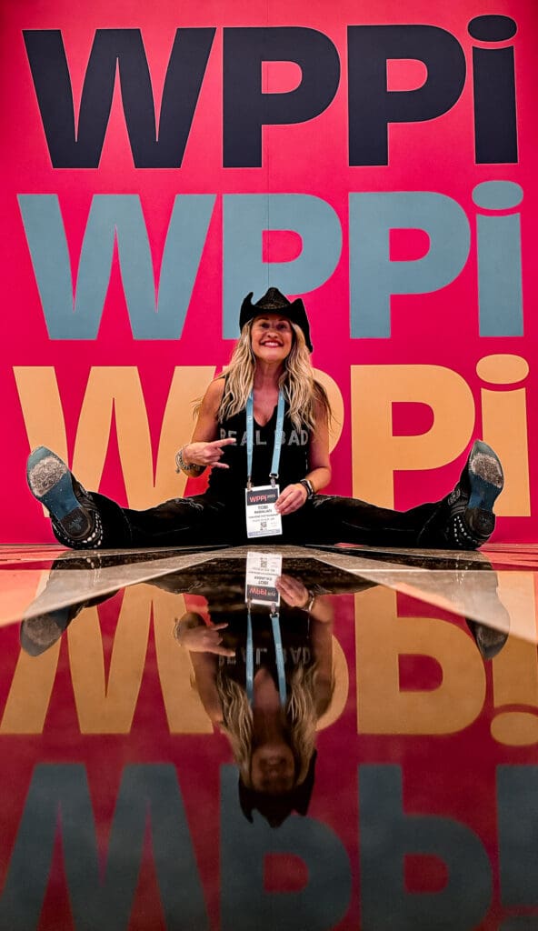 Photographer Tobi Rose Rabaliati at WPPI 2025 in Las Vegas in front of a colorful WPPI display